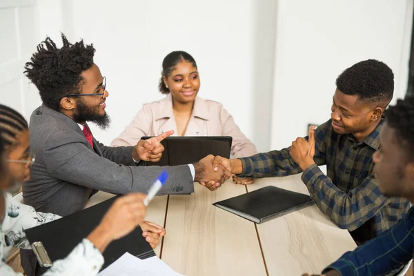 Masadaki ofisteki genç Afrikalı insanlardan oluşan bir ekip.