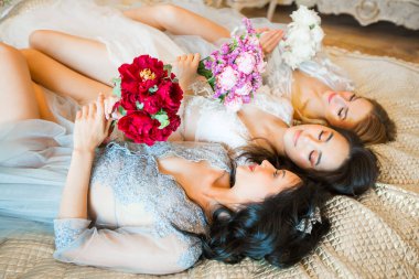  Çiçek buketleri olan üç güzel kadın kanepede yatıyor.
