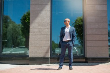 Yazlık takım elbiseli yakışıklı genç adam güneş gözlükleriyle yürüyüşe çıkmış.