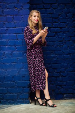 Parlak renkli bir duvarın yanında telefonu olan güzel genç bir kadın.