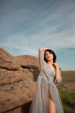 Güzel, genç bir bayan. Makyajlı ve saç stili. Nazik bir düğün geceliği içinde.