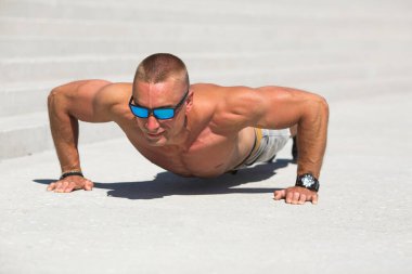 Kaslı, yakışıklı, beyaz tenli bir erkek yazın açık havada spor yapıyor.