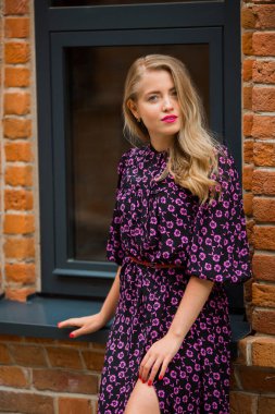 Pencerenin yanındaki yazlık elbisesiyle güzel, genç bir bayan.