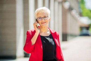 Yazın şehirde telefonu olan kısa saçlı ve gözlüklü yaşlı güzel bir kadın.