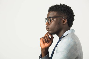 Beyaz arka planda ceketli, gözlüklü, yakışıklı, Afrikalı bir erkek.