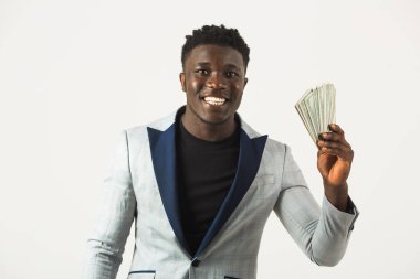 Ceketli yakışıklı bir Afrikalı erkek, beyaz bir arka planda, ellerinde dolarlarla.