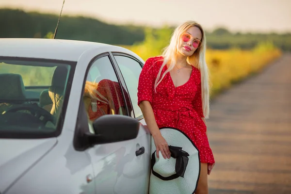 夏天的时候 穿着红色衣服 戴着粉色眼镜 站在车子旁边的美丽的年轻女子 — 图库照片