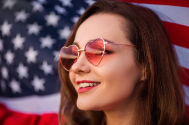 Amerikan bayrağıyla pembe güneş gözlüklü güzel bir kadın.