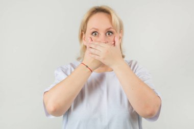 Beyaz bir arka planda beyaz tişörtlü, korkmuş yüzlü, güzel, tombul bir kadın.