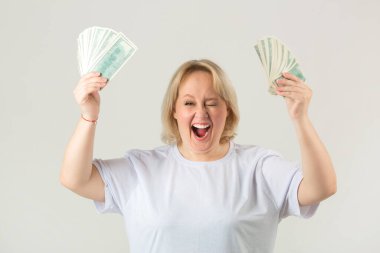 Beyaz arka planda beyaz tişörtlü, tombul, güzel bir kadın. Elinde dolarlarla.