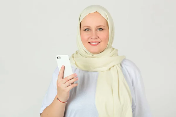 穿着白穆斯林头巾 手里拿着电话的年轻貌美的胖女人 — 图库照片