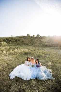 Doğada gelinlik giymiş üç güzel kadın.