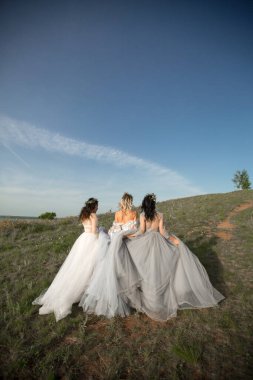 Doğada gelinlik giymiş üç güzel kadın.