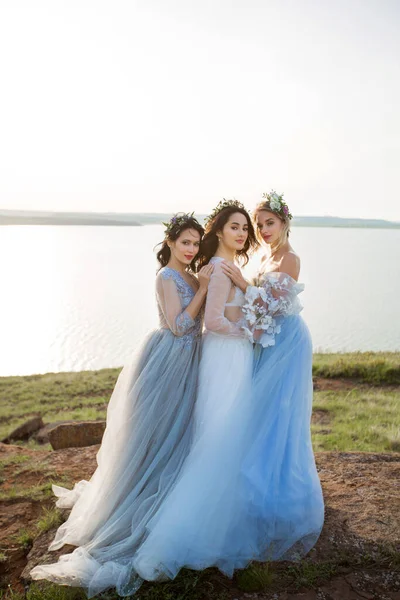 Doğada gelinlik giymiş üç güzel kadın.