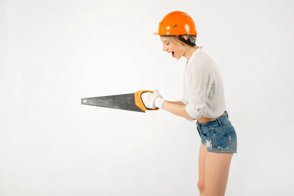 beautiful young female in a construction helmet with a saw in hand