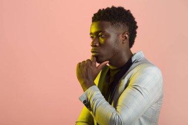 Pembe arka planda ceketli yakışıklı Afrikalı bir erkek.