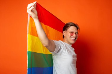 Kırmızı arka planda lgbt bayrağı olan yakışıklı genç adam.