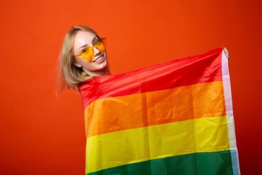 Kırmızı arka planda lgbt bayrağı olan güzel genç bir kadın.