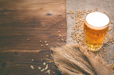 Yaşlı ahşap masa arka plan atlama ve malt ve çavdar kulaklara bardak hafif bira ile dağılmış.