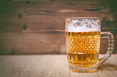 Cam ve ahşap masa arka plan üzerinde köpüklü hafif bira. Önden görünüm. Alkol arka plan kopya alanı ile.