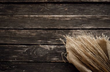 Yaşlı ahşap masa arka plan kopya alanı ile üzerine çuval bezi kumaş sarılmış çavdar kulaklar.