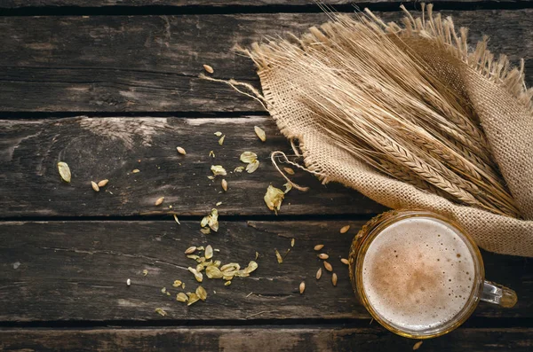 Yaşlı ahşap masa arka plan atlama ve malt ve çavdar kulaklara bardak hafif bira ile dağılmış.