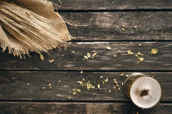 Yaşlı ahşap masa arka plan atlama ve malt ve çavdar kulaklara bardak hafif bira ile dağılmış.