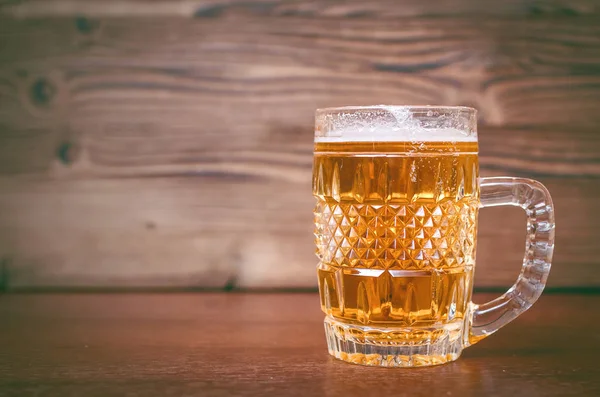 Ahşap masa arka plan üzerinde köpüklü light bira bardak.