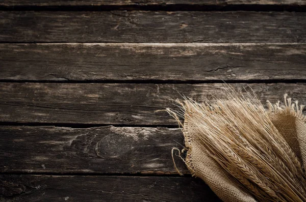 Yaşlı ahşap masa arka plan kopya alanı ile üzerine çuval bezi kumaş sarılmış çavdar kulaklar.
