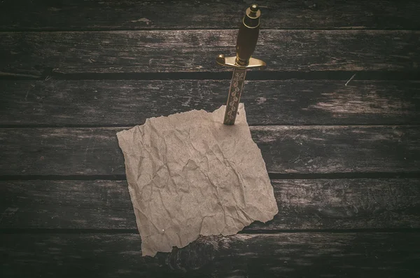 Buruşuk kahverengi kağıt sayfa parşömen ve hançerin bir tabloda itme. Maceracı hazine avcısı ya da korsan kavramı geçmiş.