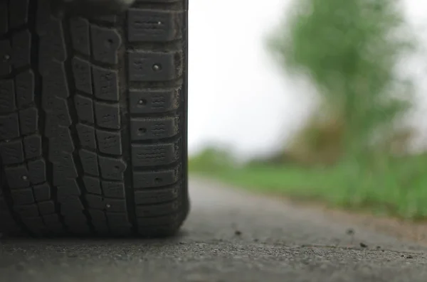 Car tyre close up on the empty asphalt road in the cloudy rainy day with copy space. Car travel concept.