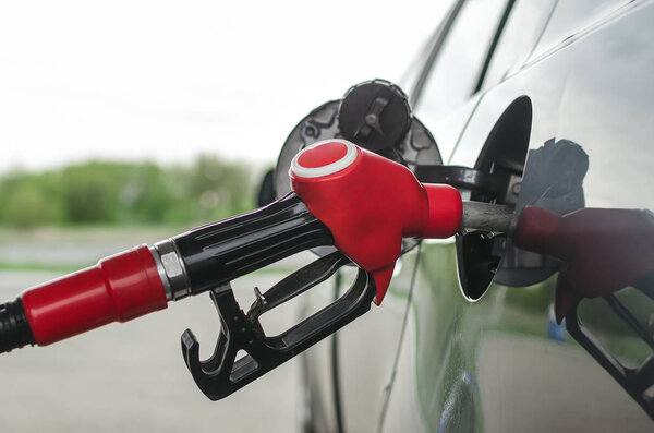 Fuel nozzle in the car gas tank close up photo. Car gas station. Refueling concept.