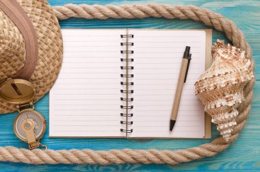 Yaz tatil arka plan çerçeve. Boş not defteri sayfaları, pusula, deniz kabuğu, mavi ahşap arka plan kopya alanı ile ip ve turist şapka.