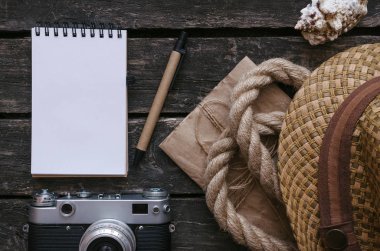 Turist veya maceracı Not defteri günlüğü kitap. Yapılacaklar listesi için. Not defteri, fotoğraf makinesi, ip, şapka ve seashell vintage tablo arka plan üzerinde.