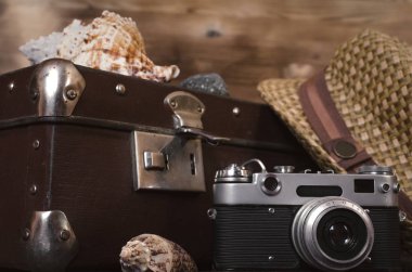 Retro yaz deniz tatil arka plan. Vintage çanta, film fotoğraf makinesi, şapka ve kabukları turist masada. Önden görünüm, yakın çekim fotoğraf.