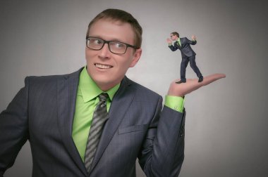 Meraklı ve hayret iş adamı dikkatle diğer kişi gri arka plan üzerinde izole palm elini dinler. Sır kavramı söylüyorum. Yalanlar.