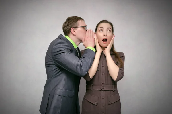 Meraklı ve hayret genç kadın üzerinde gri arka plan izole bir işadamı dikkatle dinler. Sır kavramı söylüyorum. Yalanlar.