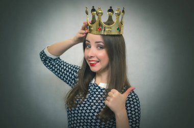 Mutlu kadın elinde altın bir taç başını tutan ve bir başparmak gösterir. Kazanan kavram. İlk yer. Yetki.