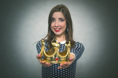 Mutlu kadın öncesinde altın bir taç gri arka plan üzerinde izole germe. Ödül töreni. Güç veya otorite transferi. İlk yer vermek.