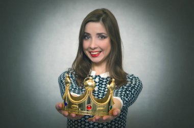 Mutlu kadın öncesinde altın bir taç gri arka plan üzerinde izole germe. Ödül töreni. Güç veya otorite transferi. İlk yer vermek.