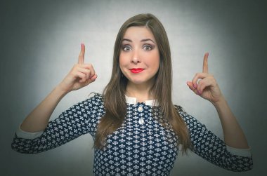 Mutlu unconcern kız onun işaret parmakları üzerinde kopya alanı tarafından kafasını ve gülümseyen izole üzerinde gri arka plan üzerinde görünüyor. Özel fırsat. Telefon numarası iletişim.