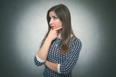 Dalgın dalgın merak ve gri arka plan üzerinde izole düşünme kadındır. Hayal kırıklığına kız.