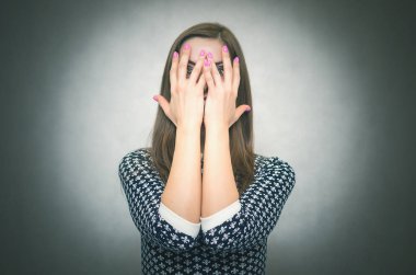 Kızgın agresif kadın şok içinde bağırarak ve gri arka plan üzerinde izole ellerini yüzüne yakın. 