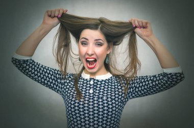 Şok sürpriz kadın saçlarını tarafından elleri üzerinde bir kafa tutuyor ve izole üzerinde gri arka planda çığlık atıyor. Aniden. Kazanmak.