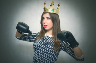 Altın taç başında ve boks eldivenleri ile kızgın kendine güvenen kadın. Kötü ruh kavramı ukala kız. Memnun karısı. Kadın maç. Kadın güzellik yarışması kavramı. Kadın rekabet.