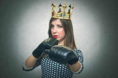 Altın taç başında ve boks eldivenleri ile kızgın kendine güvenen kadın. Kötü ruh kavramı ukala kız. Memnun karısı. Kadın maç. Kadın güzellik yarışması kavramı. Kadın rekabet.