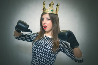 Altın taç başında ve boks eldivenleri ile kızgın kendine güvenen kadın. Kötü ruh kavramı ukala kız. Memnun karısı. Kadın maç. Kadın güzellik yarışması kavramı. Kadın rekabet.