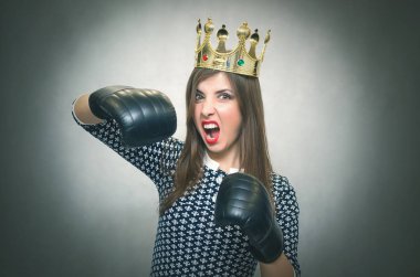 Altın taç başında ve boks eldivenleri ile kızgın kendine güvenen kadın. Kötü ruh kavramı ukala kız. Memnun karısı. Kadın maç. Kadın güzellik yarışması kavramı. Kadın rekabet.