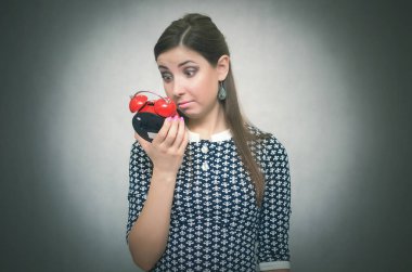 Elinde kırmızı bir çalar saat tutan şok kadın uyuya kalmışım. Okulda veya geç. Fazla uyumak. Kilise kavramı.