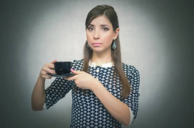 Kahve molası. Kahve zamanı. Öğle yemeği molası. Ciddi ve kendinden emin bir kadın elinde bir fincan kahve gri arka plan üzerinde izole tutan. Kahve kavramı için ihtiyaç.